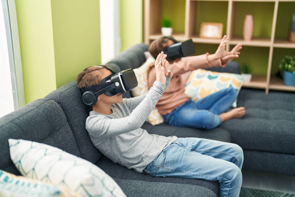 Evde sanal gerçeklik gözlüğü kullanarak video oyunu oynayan iki çocuk. - Fotoğraf, Görsel