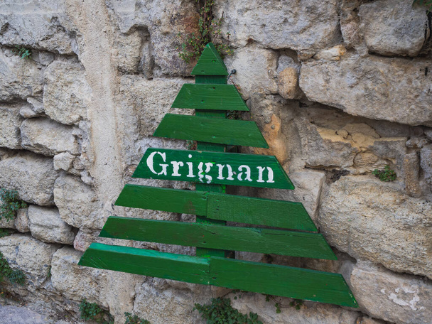 Зеленая деревянная елка, рождественские украшения на улице в Гриньяне. Каменный фон - Фото, изображение