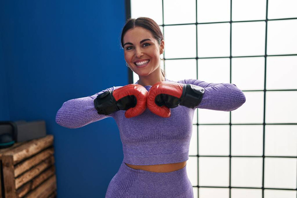 Young beautiful hispanic woman smiling confident boxing at sport center - 写真・画像