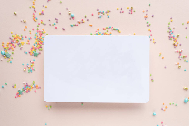 white paper mockup with texture on festive peach background with confetti, invitation mockup, top view - Foto, Imagen