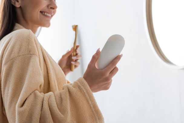 cropped view of happy young woman holding toothbrush and toothpaste in morning  - Foto, Imagem