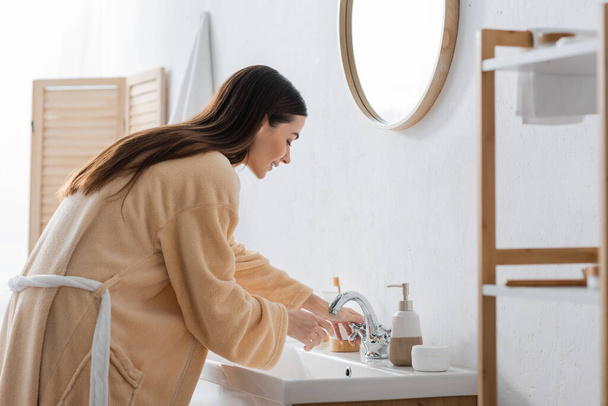 side view of young brunette woman with long hair having morning routine in bathroom  - Photo, Image