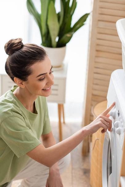 Young brunette woman switching washing machine in laundry room  - Foto, Imagem
