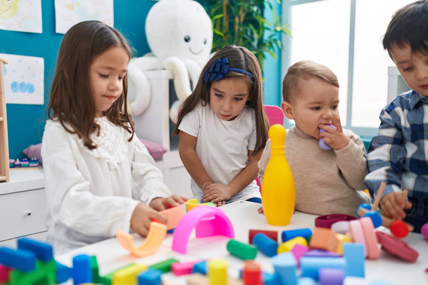 Group of kids playing with construction blocks sitting on table at kindergarten - Foto, imagen