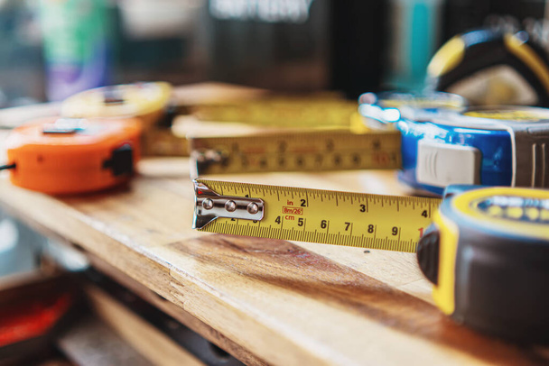 Cinta métrica o cinta métrica con marcas medidas lineales y herramientas manuales de carpintería en escritorio de madera, fabricante de bricolaje y concepto de carpintería. enfoque selectivo - Foto, imagen