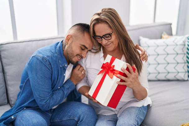 Man and woman mother and son surprise with gift hugging at home - Photo, Image