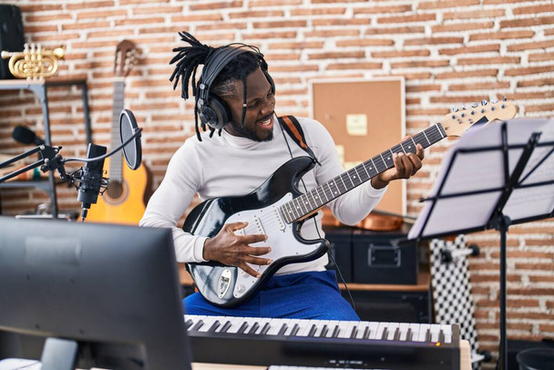 Artista afroamericana cantando canción tocando guitarra eléctrica en estudio de música - Foto, imagen