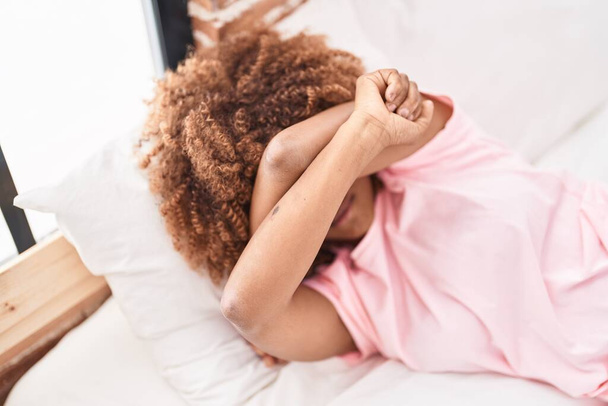 Afroamerikanerin gestresst auf Bett im Schlafzimmer liegend - Foto, Bild