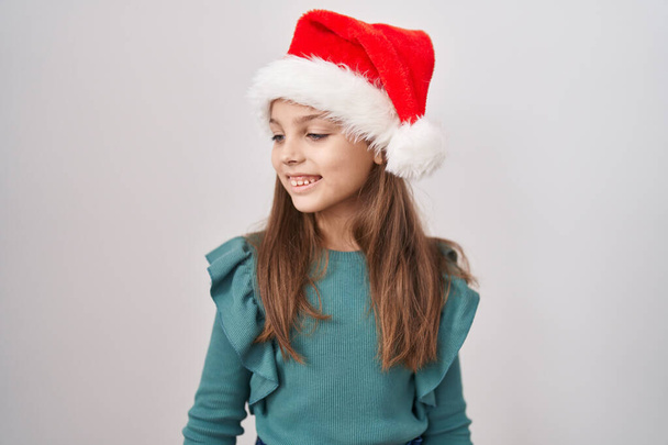 Kis kaukázusi lány visel karácsonyi kalap néz oldalra, pihenni profil pózol természetes arc és magabiztos mosoly.  - Fotó, kép