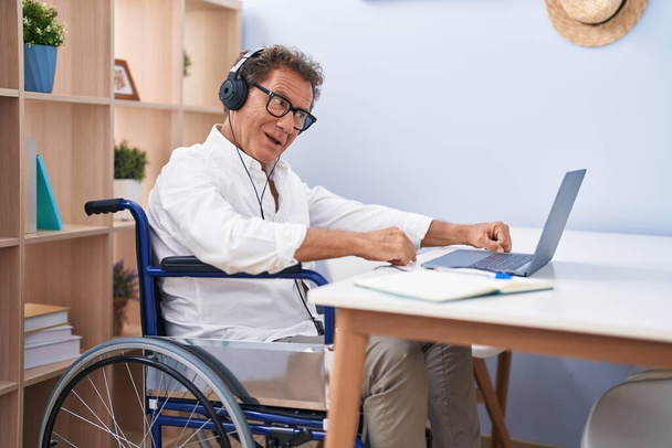 Мужчина средних лет, сидящий на инвалидной коляске и работающий дома - Фото, изображение