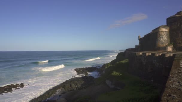 Castillo San Felipe del Morro vagy el Morro San Juanban, Puerto Ricóban. Összeomló hullámok a tengerparti erődnél. A gyarmati Spanyolország, Puerto Rico és az Egyesült Államok zászlói. A második világháború módosításai a spanyol erőd. - Felvétel, videó