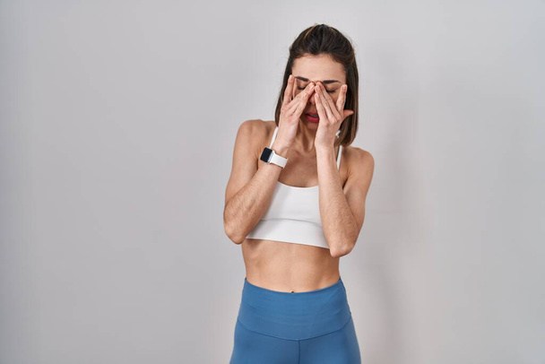 Hispanic woman wearing sportswear over isolated background rubbing eyes for fatigue and headache, sleepy and tired expression. vision problem  - Photo, Image