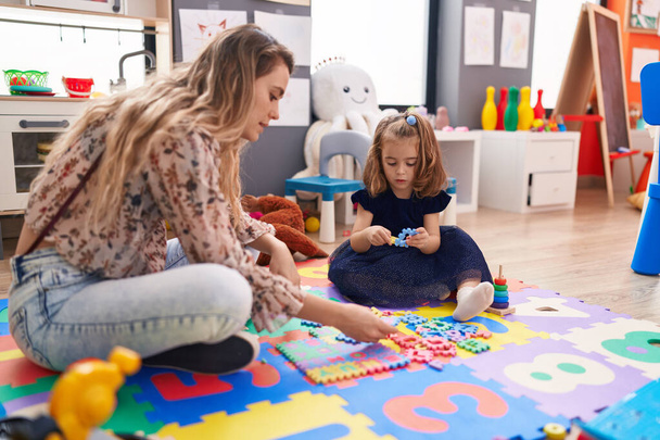 Tanár és kisgyermek játszik matematika puzzle játék ül a padlón óvoda - Fotó, kép