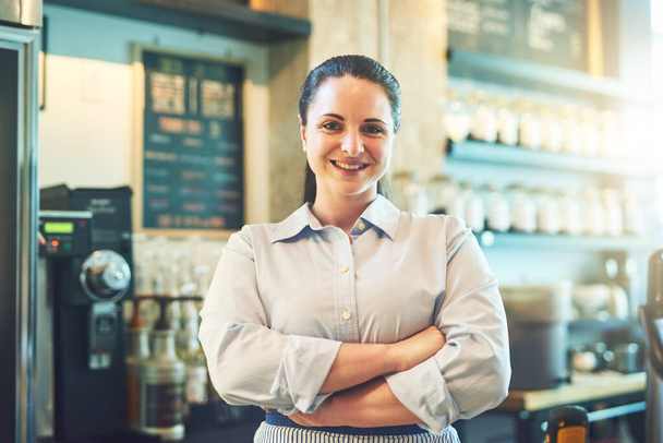Моя работа просто держать клиентов счастливыми. Портрет молодой женщины, работающей в кафе - Фото, изображение