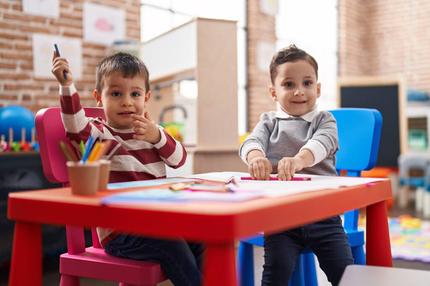 Two kids preschool students sitting on table drawing on paper at kindergarten - Photo, Image