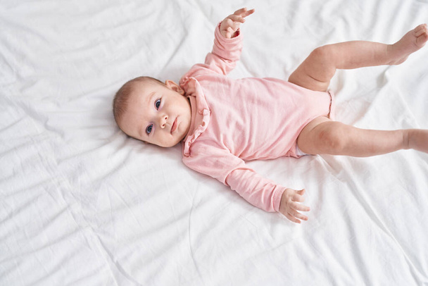 Adorable caucasian baby smiling confident lying on bed at bedroom - Fotó, kép