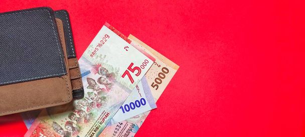 Вид на кошелек и новые индонезийские купюры рупий, выпущенные в 2022 году. Концепция валютной рупии выделена на красном фоне. Отрицательное пространство - Фото, изображение