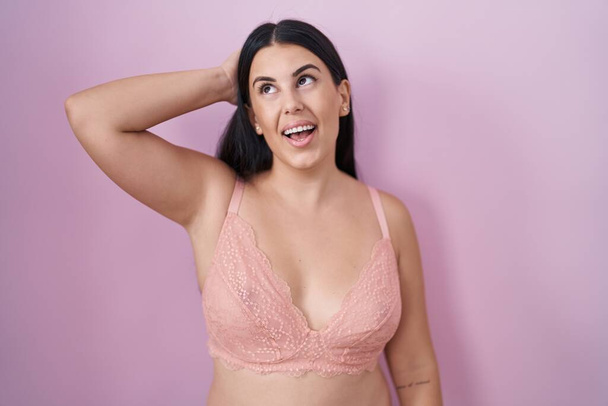 Young hispanic woman wearing pink bra smiling confident touching hair with hand up gesture, posing attractive and fashionable  - Photo, Image