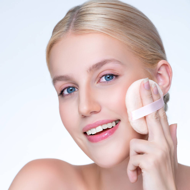 Closeup personable beautiful natural soft makeup woman using powder puff for facial makeup concept. Cushion foundation applying on young girl face in isolated background. - Photo, Image