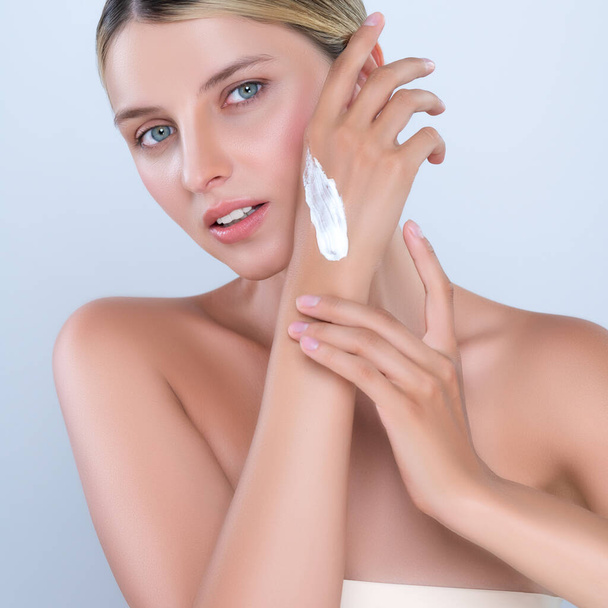 Alluring beautiful woman applying moisturizer cream on her hand for perfect skincare treatment in isolated background. Caucasian women portrait with skin rejuvenation and cosmetology concept. - Foto, Imagem