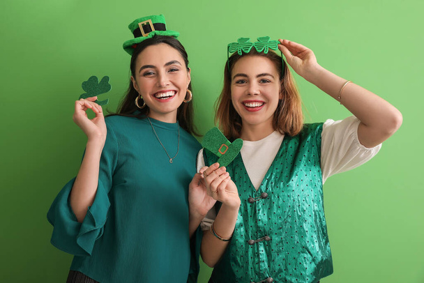 Giovani donne con trifoglio di carta e cappello su sfondo verde. Festa di San Patrizio - Foto, immagini