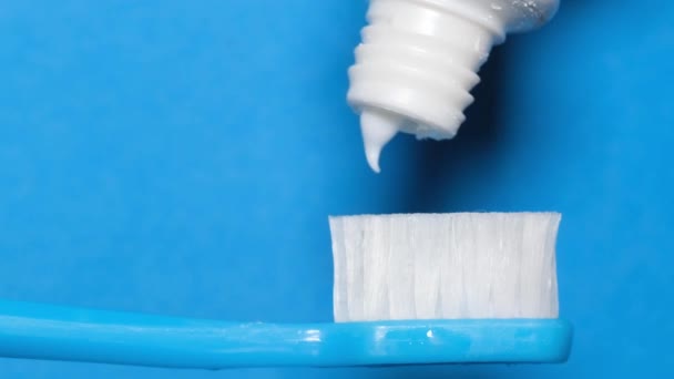 Close-up of toothpaste flowing from a tube onto a toothbrush. Morning tooth brushing. Daily oral hygiene. Slow motion - Záběry, video