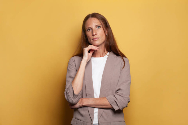 Mid adult business woman standing against yellow banner background - Photo, Image