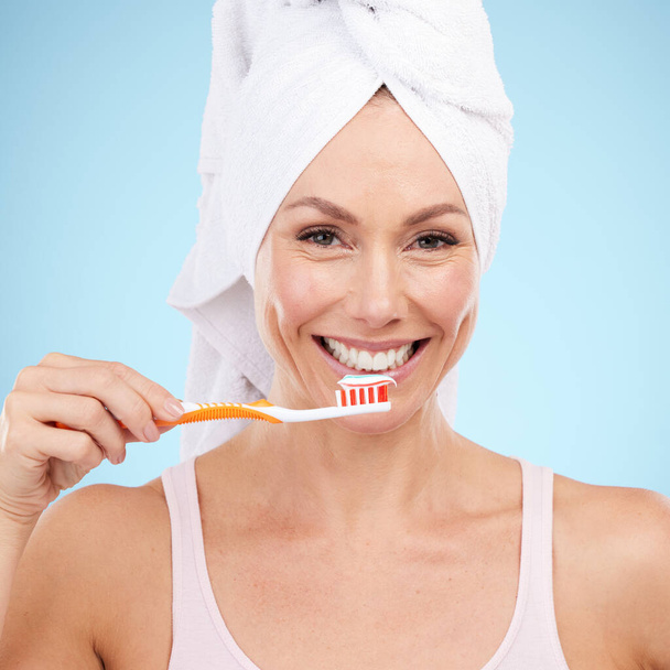 Portrait, sourire de femme et brosse à dents isolés sur fond bleu pour la santé dentaire, buccale ou orthodontique. Modèle de beauté ou personne mature pour brosser les dents, le produit de nettoyage et le dentifrice en studio. - Photo, image