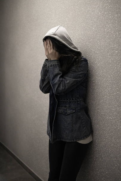 драматическая концепция, силуэт грустной депрессии женщины, стоящей головой в руках у стены. - Фото, изображение