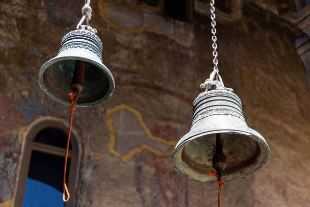 Два железных колокола, свисающие с потолка в Успенской церкви с красочными средневековыми фресками в пещерном монастырском комплексе Вардзия, Джорджия. - Фото, изображение