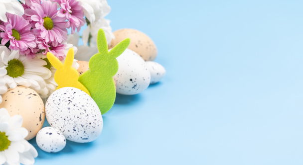 Easter eggs, rabbit decor and flower bouquet on a blue background with space for your greetings. Flat lay - Photo, Image