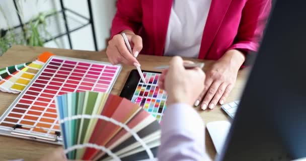 Σχεδιαστής βοηθά τον πελάτη να επιλέξει το χρώμα από την ποικιλία των δειγμάτων στο γραφείο στο tablet. Διαδικασία επιλογής χρωματικής λύσης στο στούντιο τέχνης - Πλάνα, βίντεο