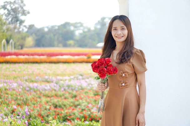Mujer asiática sonriendo felizmente entre hermosas flores - Foto, Imagen