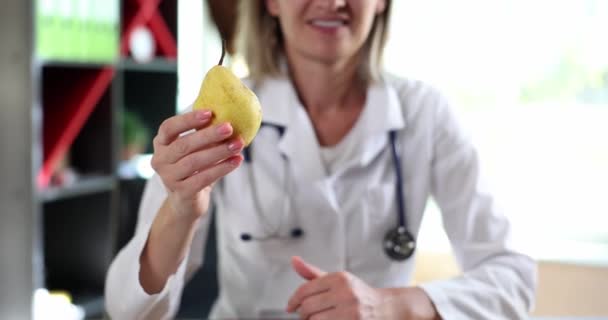 Γιατρός διατροφολόγος με αχλάδι κρατά τους αντίχειρες επάνω. Συστάσεις και συμβουλές για υγιεινή διατροφή και βιταμίνες - Πλάνα, βίντεο