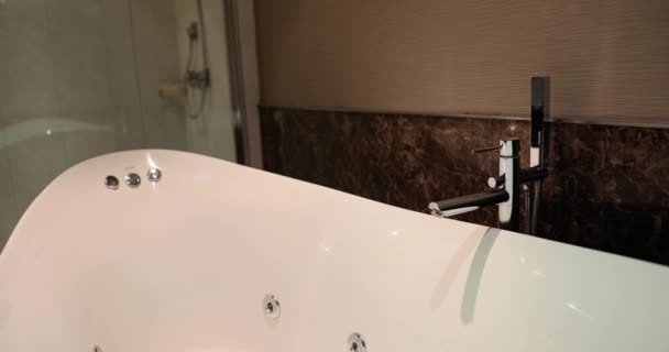 Интерьер ванной комнаты в уютных тонах с современной ванной. Красивая стильная ванна в номере отеля - Кадры, видео