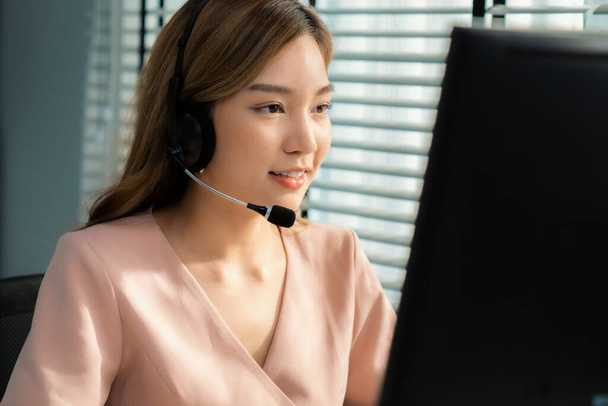 Competent female operator working on computer and while talking with clients. Concept relevant to both call centers and customer service offices. - Zdjęcie, obraz