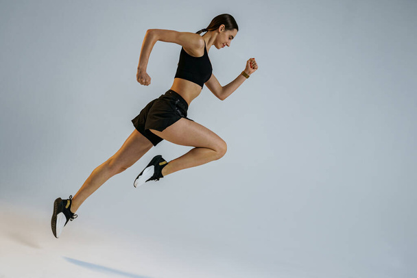 Atletica donna attiva che salta su sfondo studio. Movimento dinamico - Foto, immagini
