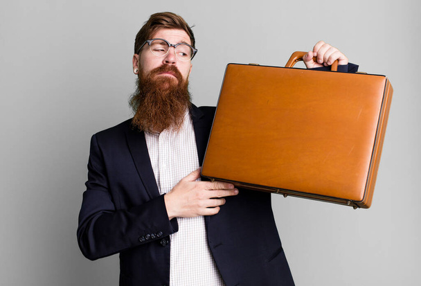 mladý dospělý zrzavé vlasy vousatý chladný podnikatel s koženým kufříkem - Fotografie, Obrázek