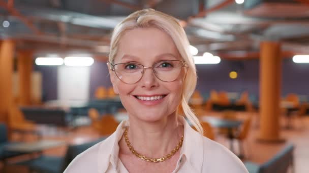 Smiling blonde mature professional businesswoman looking at camera. Happy confident beautiful smart middle age adult entrepreneur, leader manager posing in office. Close up face view business portrait - Séquence, vidéo
