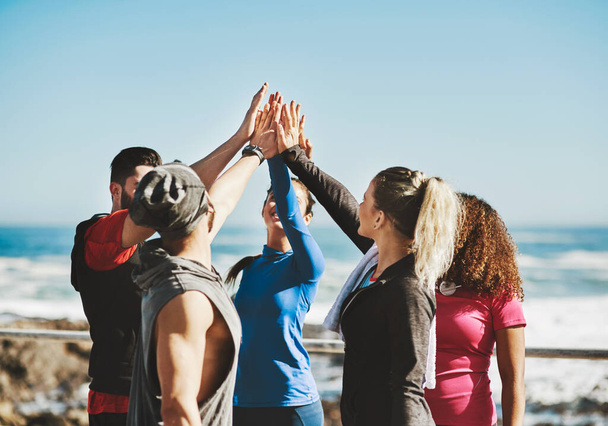 У нас получается лучше, когда мы делаем это вместе. a fitness group high-five before a run - Фото, изображение