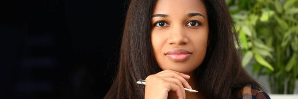 思考はペンで美しいアフロ女性に焦点を当てました.スマートダークスキンの若い女性の概念の肖像画 - 写真・画像
