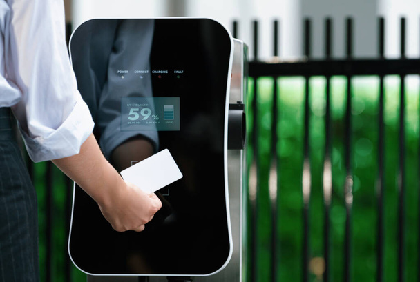 Hand holding credit card to pay public charging station and recharge her electric vehicle, symbolizing progressive lifestyle, combines e-wallet technology and sustainable transportation option. - Φωτογραφία, εικόνα