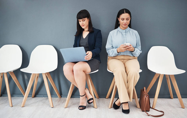Waiting room, interview and women ready for hiring meeting with laptop and phone in office building. People, employee and worker preparing for business internship or job opportunity or employment. - 写真・画像