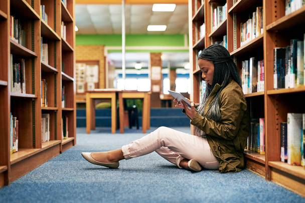 A kedvenc helye a böngészés. egyetemi hallgató, aki digitális tabletet használ a kampusz könyvtárában - Fotó, kép