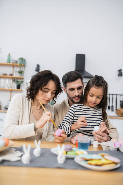 Famille avec fille peignant des œufs pendant Easer à la maison  - Photo, image