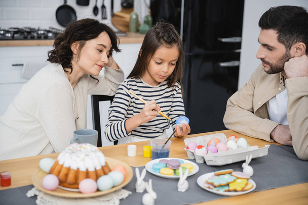 Rodina sedí v blízkosti dcery zbarvení velikonoční vejce v blízkosti potravin doma  - Fotografie, Obrázek