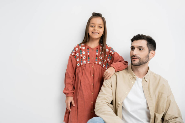Smiling preteen girl standing near bearded father on white background  - 写真・画像