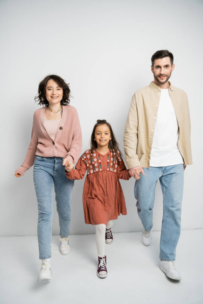 Happy family holding hands while walking on white background  - Foto, Bild