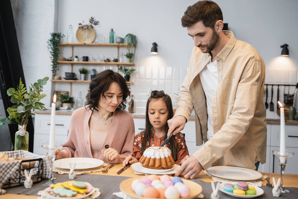 Man cutting Easter cake near family during dinner at home  - Fotoğraf, Görsel