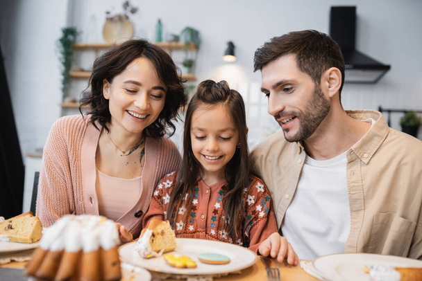 Positive parents sitting near child and Easter dinner at home  - Photo, Image